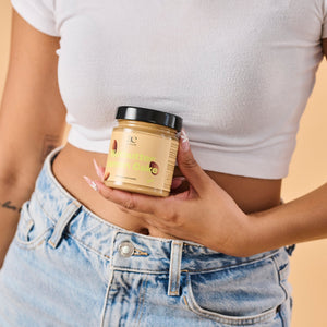 Nahaufnahme einer Frau, die ein Glas Nutbutter Lemon Cake von ae kitchen vor dem Bauch hält